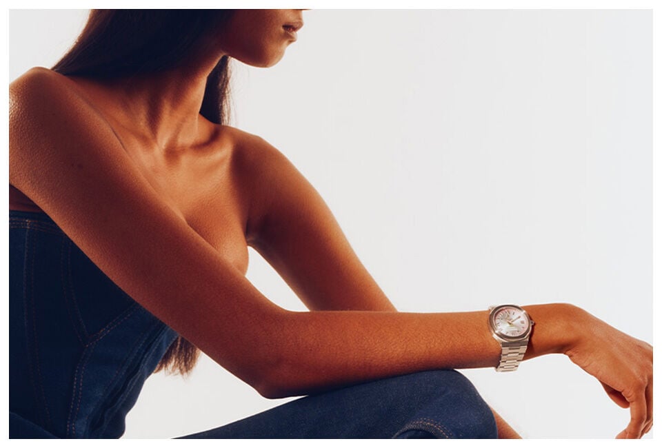 Vivienne Westwood Time Machine campaign featuring model wearing a silver bracelet watch with pink dial, styled with a strapless denim top.
